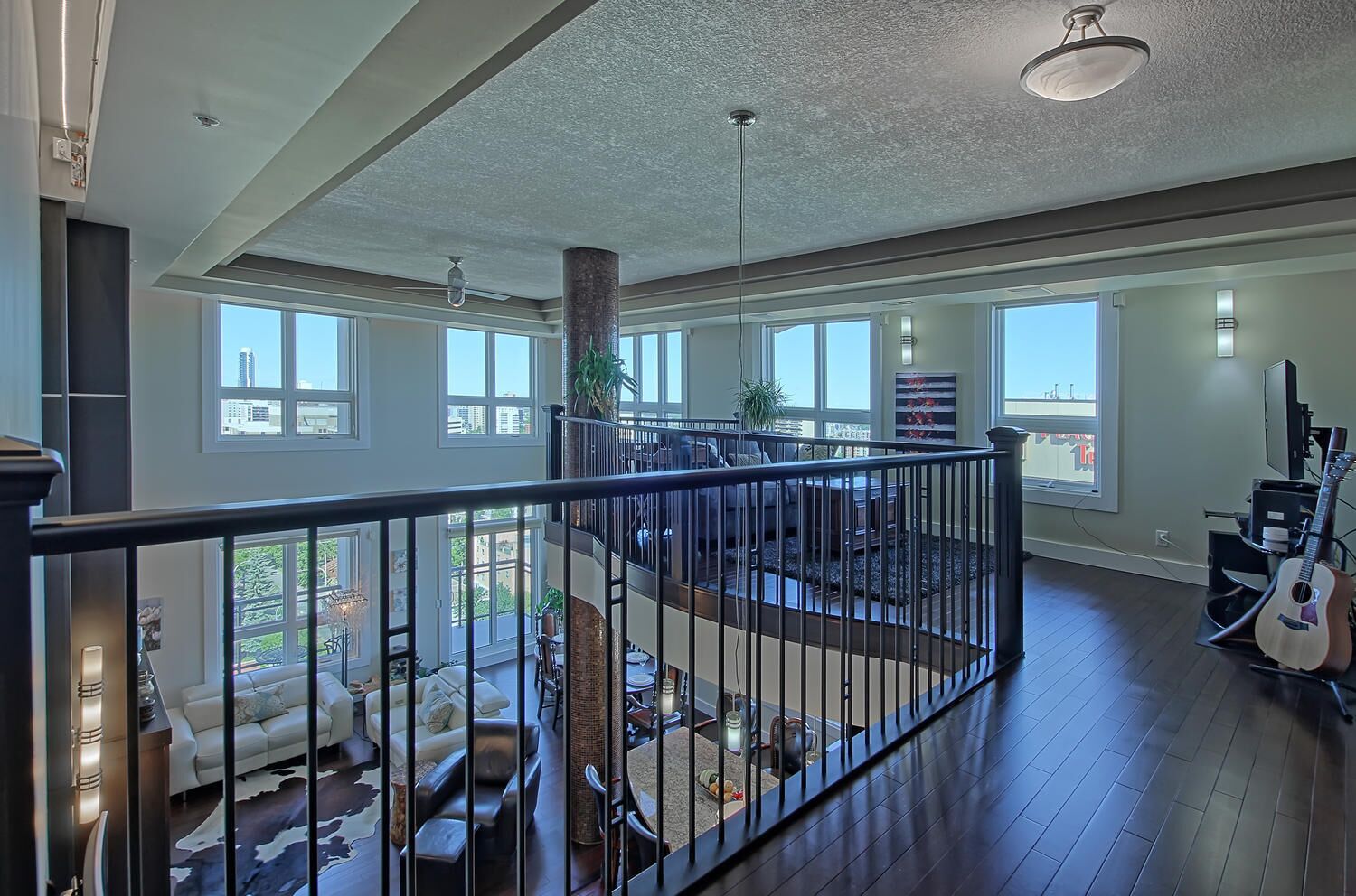 A spacious living area with a high ceiling, large windows, and a view of the outdoors.