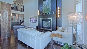 A spacious living room with a fireplace, white sofas, and a large chandelier. - Luxury Penthouse Oasis, Rooftop Patio, River View, Downtown (Edmonton)