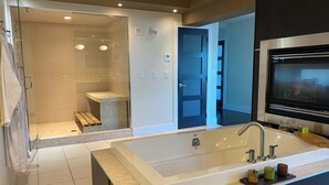 A modern bathroom with a glass-enclosed shower, a large bathtub, and a countertop with toiletries. - Luxury Penthouse Oasis, Rooftop Patio, River View, Downtown (Edmonton)