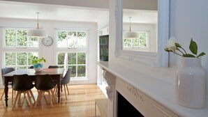 Un comedor con una mesa de madera, sillas y un reloj en la pared.