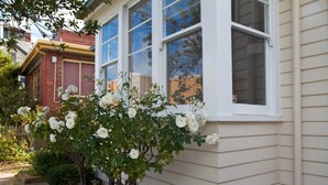 Una casa con una ventana y un arbusto en flor al frente.