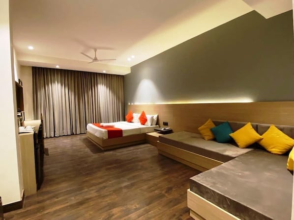 A modern hotel room with a bed, a sofa, a desk, and a large window with curtains. - Hotel Classic Residency (Kalka)