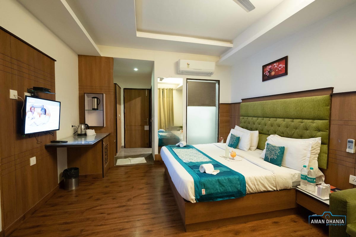 A hotel room with a bed, a desk, a television, and a bathroom.