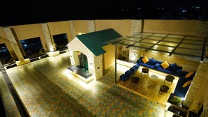 Una terraza en la azotea con un área de estar cubierta de vidrio, una pequeña construcción de piedra y un suelo con diseño.