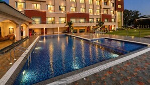 Un hotel con piscina, varios balcones e iluminación exterior.