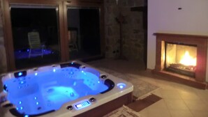 A hot tub with a digital control panel, a stone fireplace, and a view through a glass door. - B&B Le Peschiere (Montefiorino)