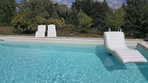 A clear swimming pool with two lounge chairs and a sunbed. - B&B Le Peschiere (Montefiorino)