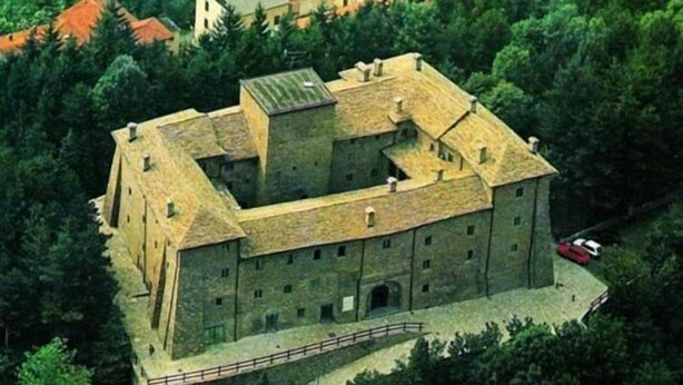 A large, historic building with multiple wings and a central courtyard, surrounded by dense greenery. - B&B Le Peschiere (Montefiorino)