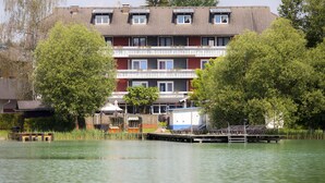 A multi-story building with balconies, a dock, and a small boat. - See & GenussHotel Silvia (Sankt Kanzian am Klopeiner See)