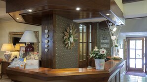 A reception area with a wooden counter, a mirror, a lamp, and a sign that reads "HOME WHERE THE HEART". - See & GenussHotel Silvia (Sankt Kanzian am Klopeiner See)