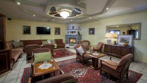 A living room with a fireplace, sofas, armchairs, a coffee table, and a rug. - See & GenussHotel Silvia (Sankt Kanzian am Klopeiner See)