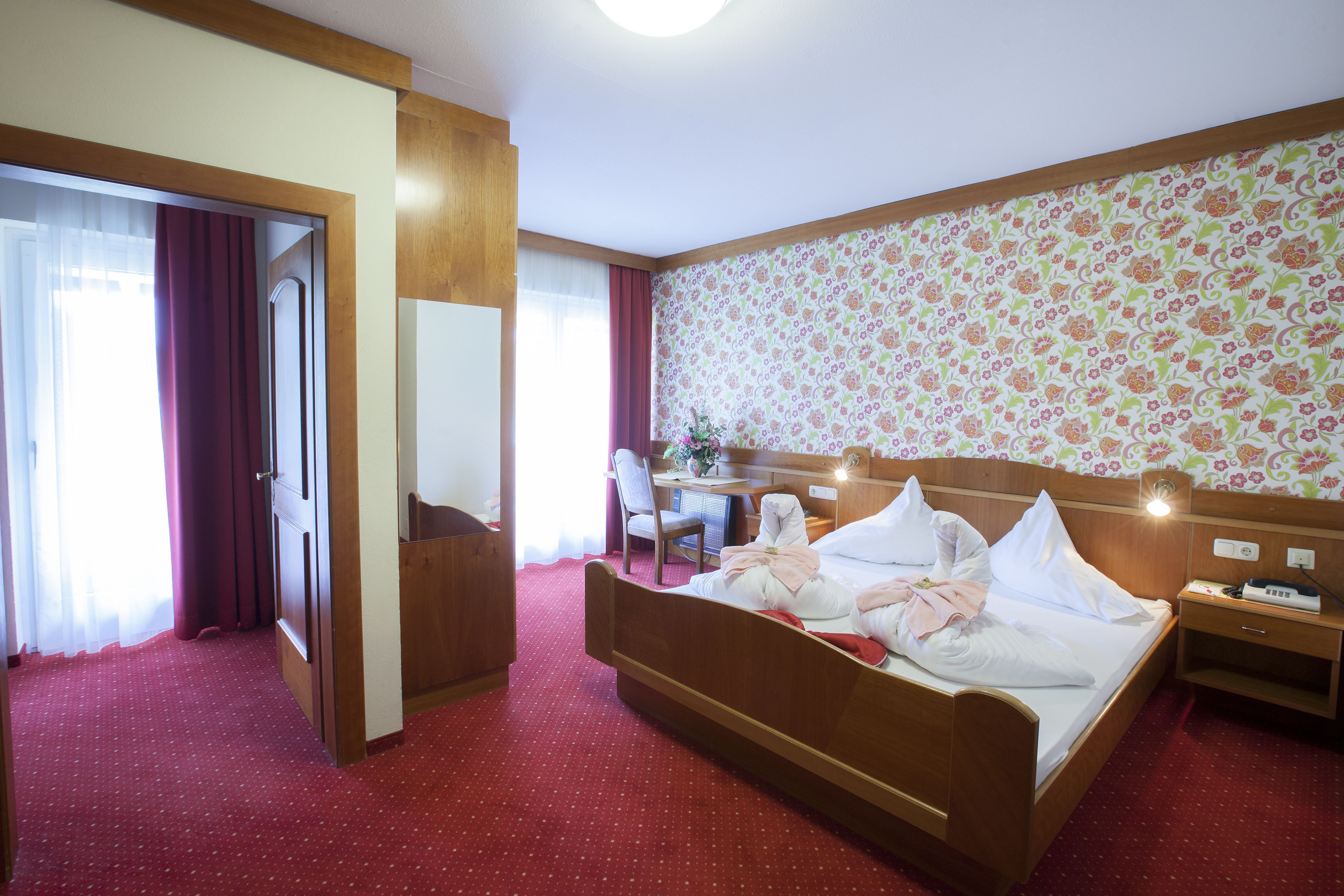 Ein Hotelzimmer mit Bett, Schreibtisch, Stuhl und Spiegel.