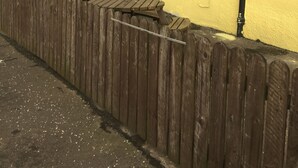 Un bâtiment jaune avec une clôture en bois, une cheminée et une enseigne sur laquelle on peut lire : « The Harvest Coaching Inn ».