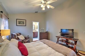 A bedroom with a bed, a chair, a dresser, a television, and a ceiling fan. - Lakefront Brandon Home w/ Patio & Screened Lanai! (Brandon)