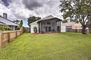 A residential backyard with a house, a wooden fence, and a tree. - Lakefront Brandon Home w/ Patio & Screened Lanai! (Brandon)