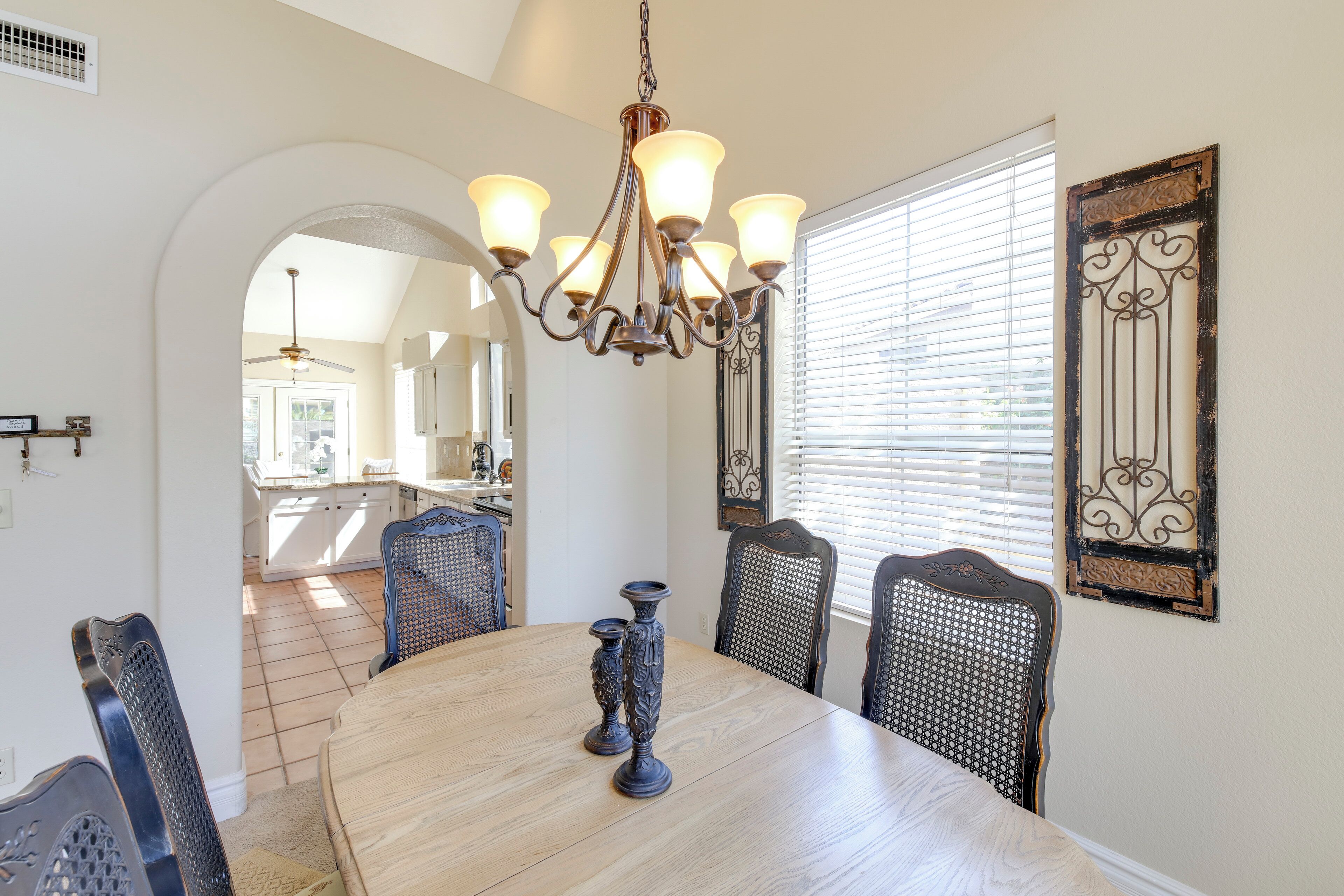 A dining room with a wooden table, chairs, and a chandelier.