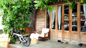 Une véranda en bois avec un vélo, une chaise et une table.