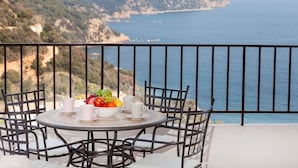 A round table with chairs and a fruit bowl on a balcony overlooking a coastal landscape. - Beautiful apartment for 4 people with WIFI, TV and terrace (Tossa De Mar)