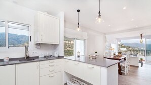 A modern kitchen with white cabinetry, a large window, and a balcony with a view of the mountains. - Beautiful apartment for 4 people with WIFI, TV and terrace (Tossa De Mar)