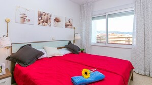 Une chambre d’hôtel avec un grand lit, une fenêtre donnant sur un beau paysage et des œuvres d’art murales.
