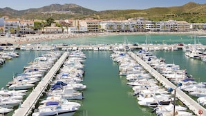 A marina with numerous boats docked, a beach with people, and buildings in the background. - Nice apartment for 5 people with WIFI, A/C, TV, terrace and pets allowed (Santa Isabel)