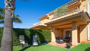 A two-story house with a patio area, outdoor furniture, and a well-maintained lawn. - Beautiful apartment for 4 people with WIFI, A/C, pool, TV and patio (Teulada)