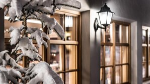 Un árbol cubierto de nieve frente a un edificio con ventanas grandes y un farol.