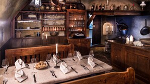 Un comedor rústico con muebles de madera, una mesa de mármol y diversos utensilios de cocina y utensilios de cocina en estantes.