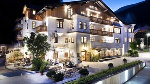 Un hotel con terraza, un restaurante y una entrada bien iluminada.