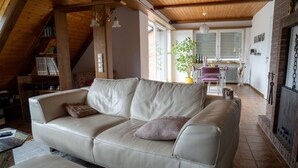 Un salon chaleureux avec un canapé, une cheminée et un coin repas comprenant une table et des chaises.