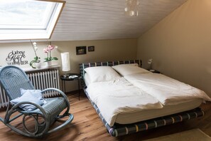 Un dormitorio con cama, una mecedora, un radiador y un tragaluz.