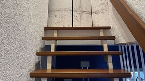 Un escalier avec des marches en bois et un mur blanc à la texture particulière.