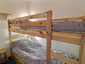 A bunk bed with a wooden frame and grey bedding.