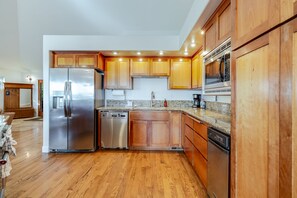 A modern kitchen with wooden cabinets, stainless steel appliances, and a granite countertop.