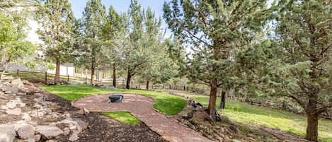 Un jardín ajardinado con un sendero de grava serpenteante, rodeado de árboles maduros y una zona cubierta de césped.
