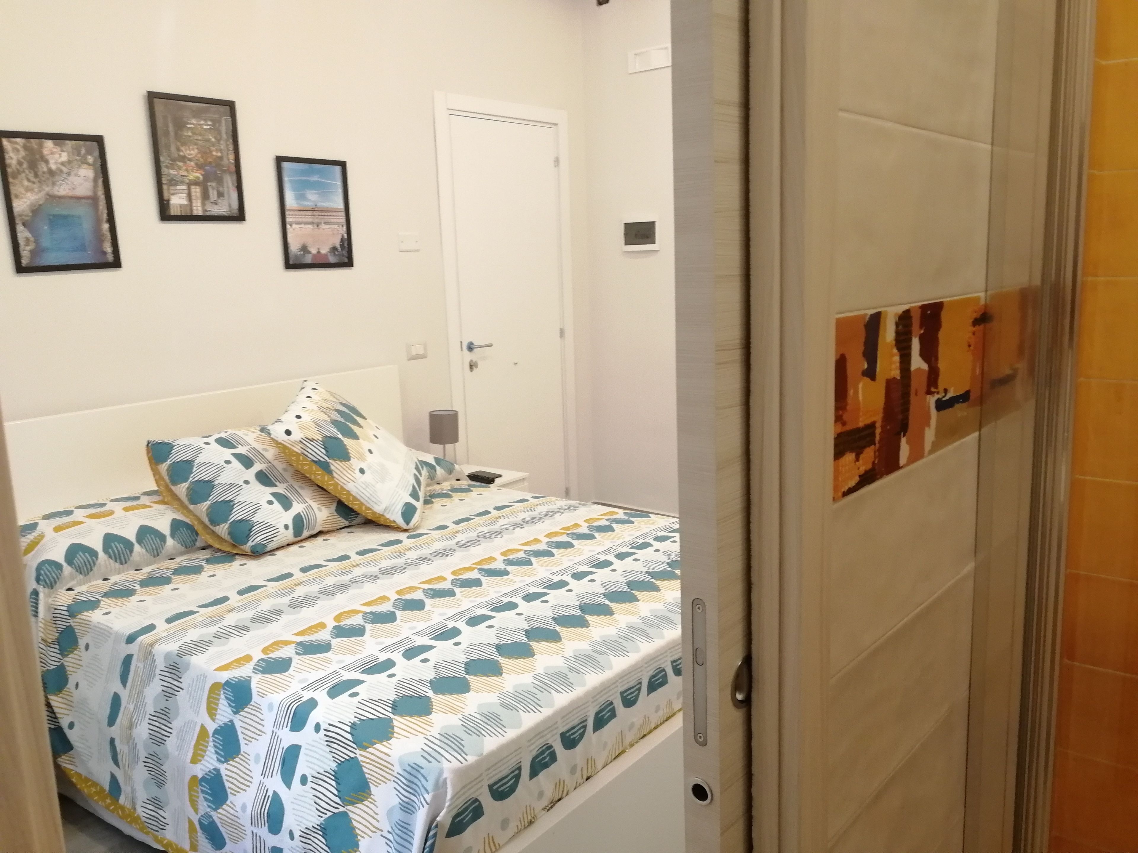 A bedroom with a bed, pillows, a bedside table, and a door.