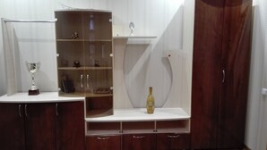 Een houten kast met meerdere planken, een wijnfles en een trofee.