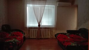 Een kamer met twee bedden, een raam met zonwering, een radiator en een airconditioning.