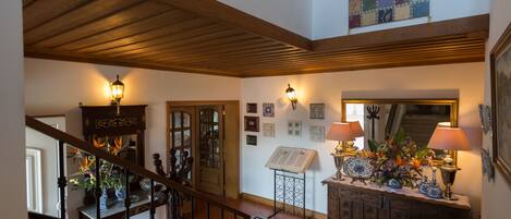 A staircase with a wooden railing, a console table with lamps, and a decorative mirror.