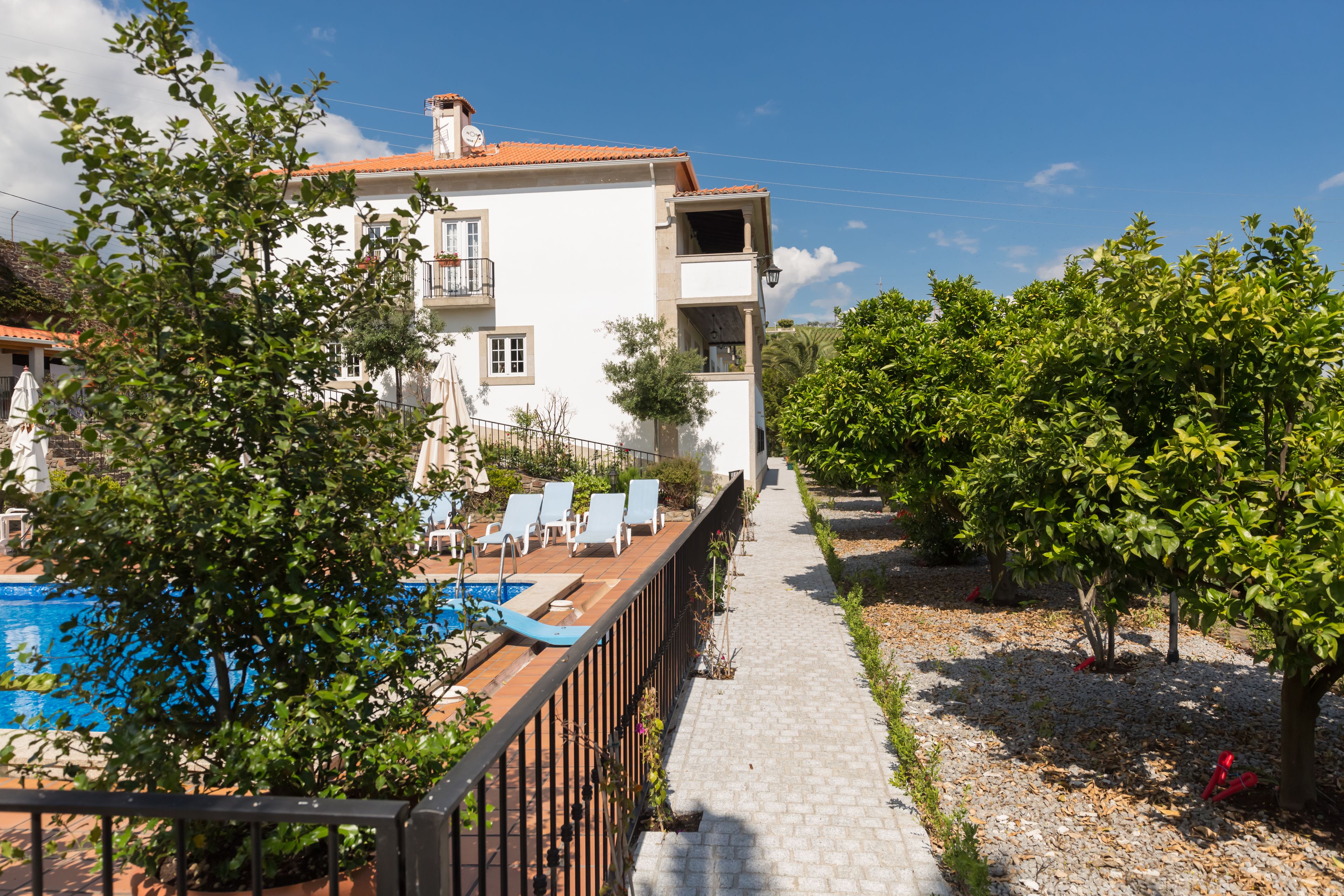 A villa with a swimming pool, outdoor seating, and a garden path.