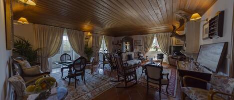 Uma sala de estar aconchegante com teto de madeira, assentos confortáveis, um espaço de refeições e uma cabeça de veado montada.