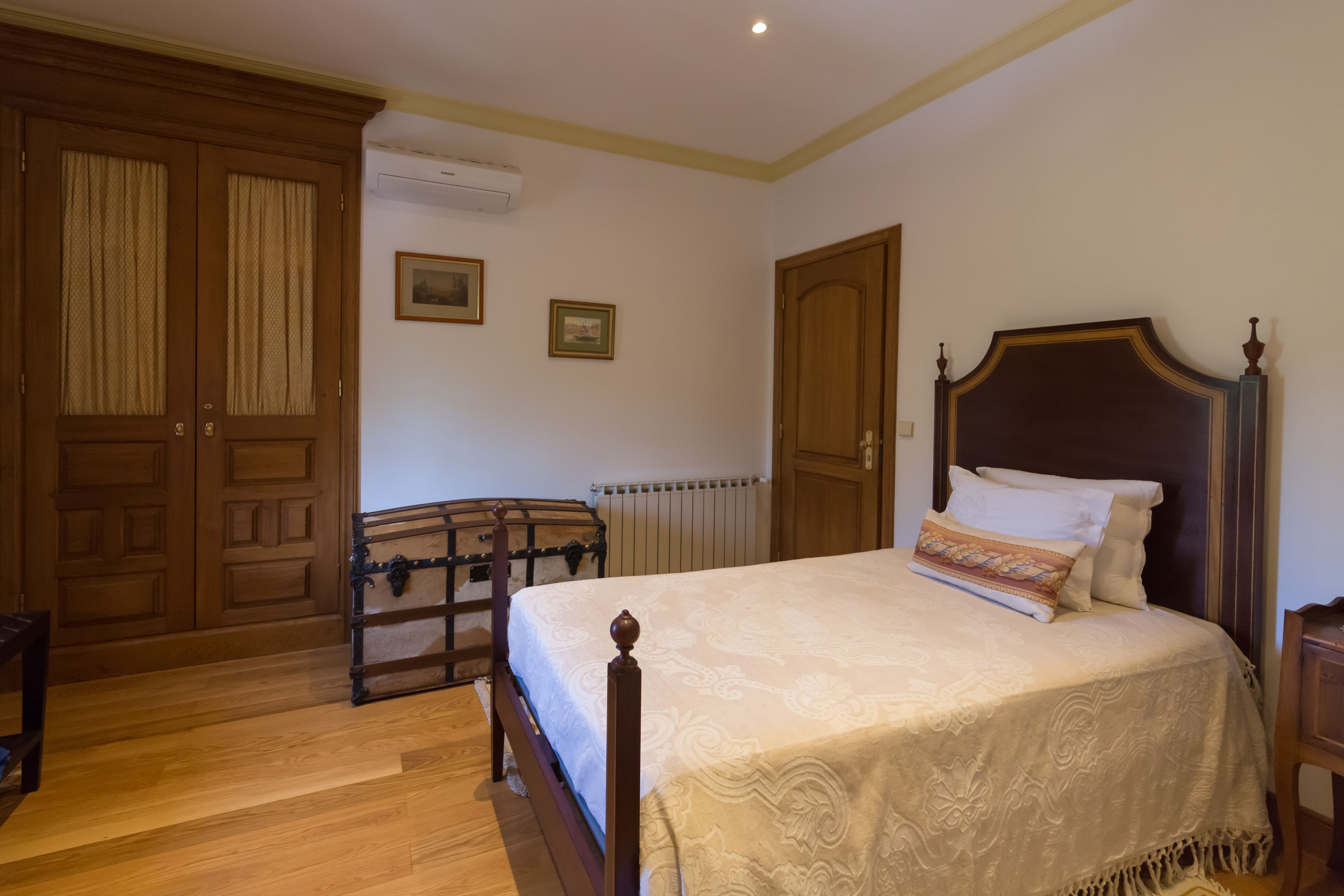 Een slaapkamer met een houten bed, een kledingkast en een radiator.