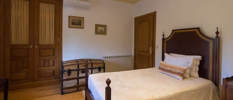A bedroom with a wooden bed, a wardrobe, and a radiator.