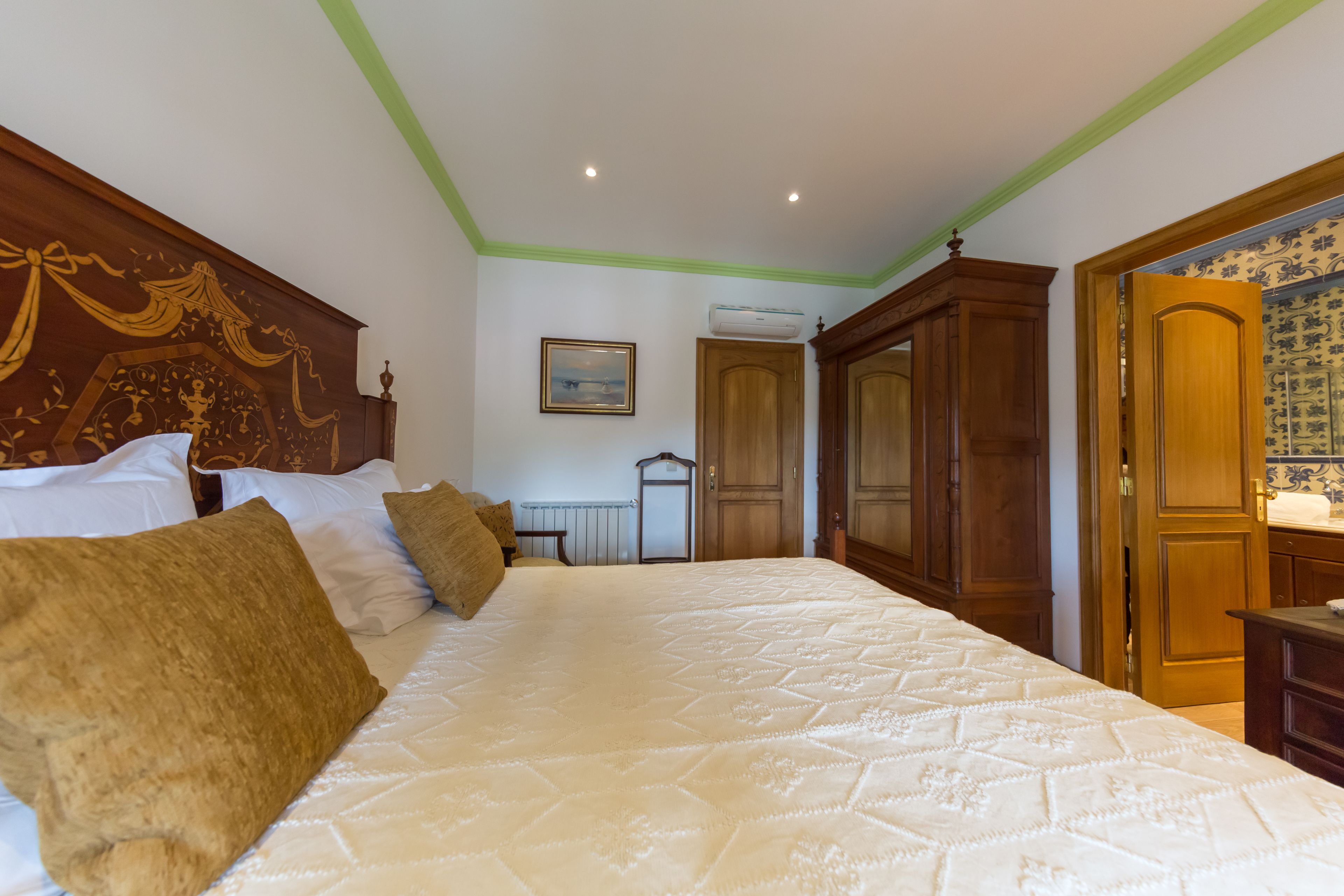 A bedroom with a large bed, wooden headboard, and a green accent wall.