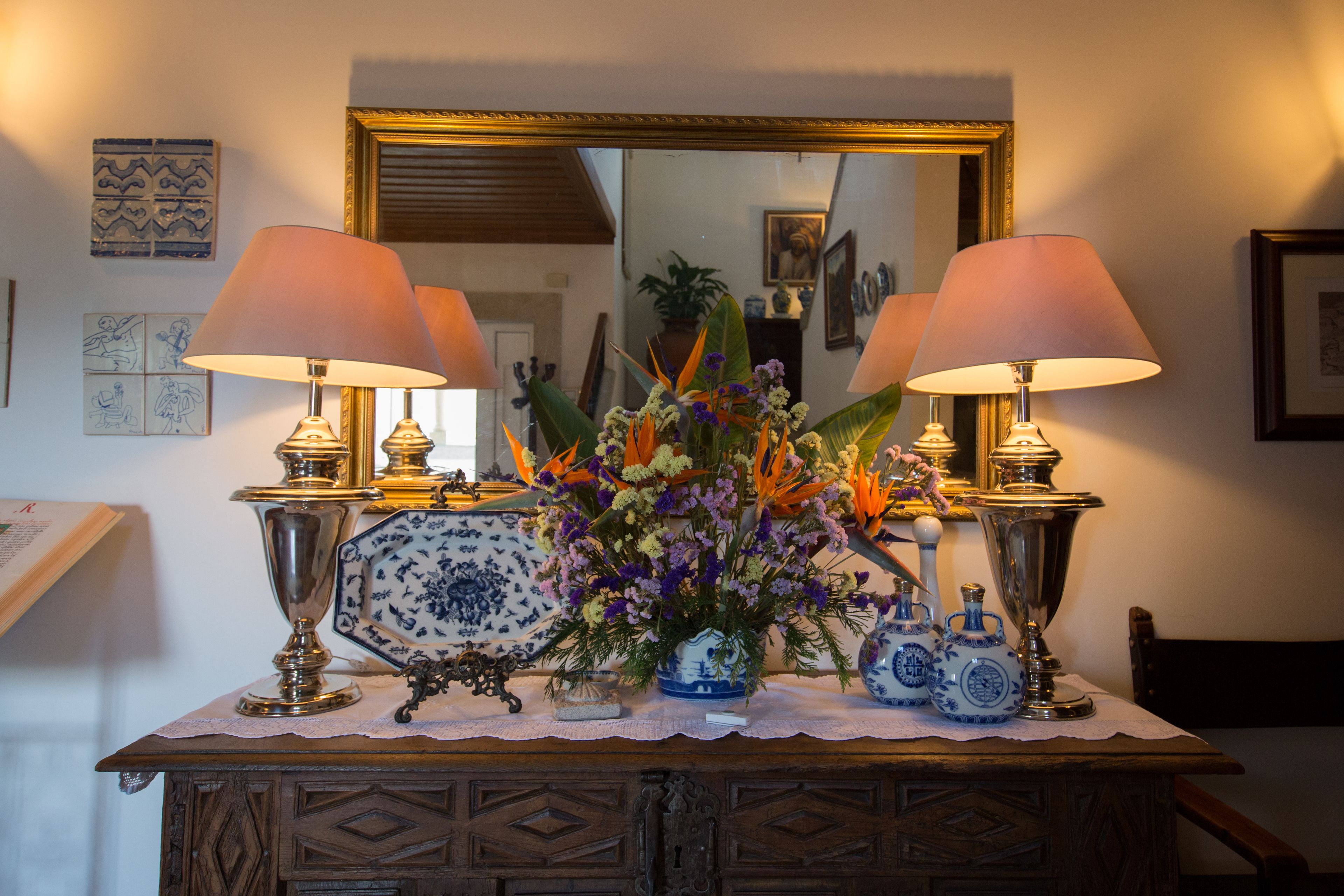 Una mesa con dos lámparas, un jarrón de flores y objetos decorativos.