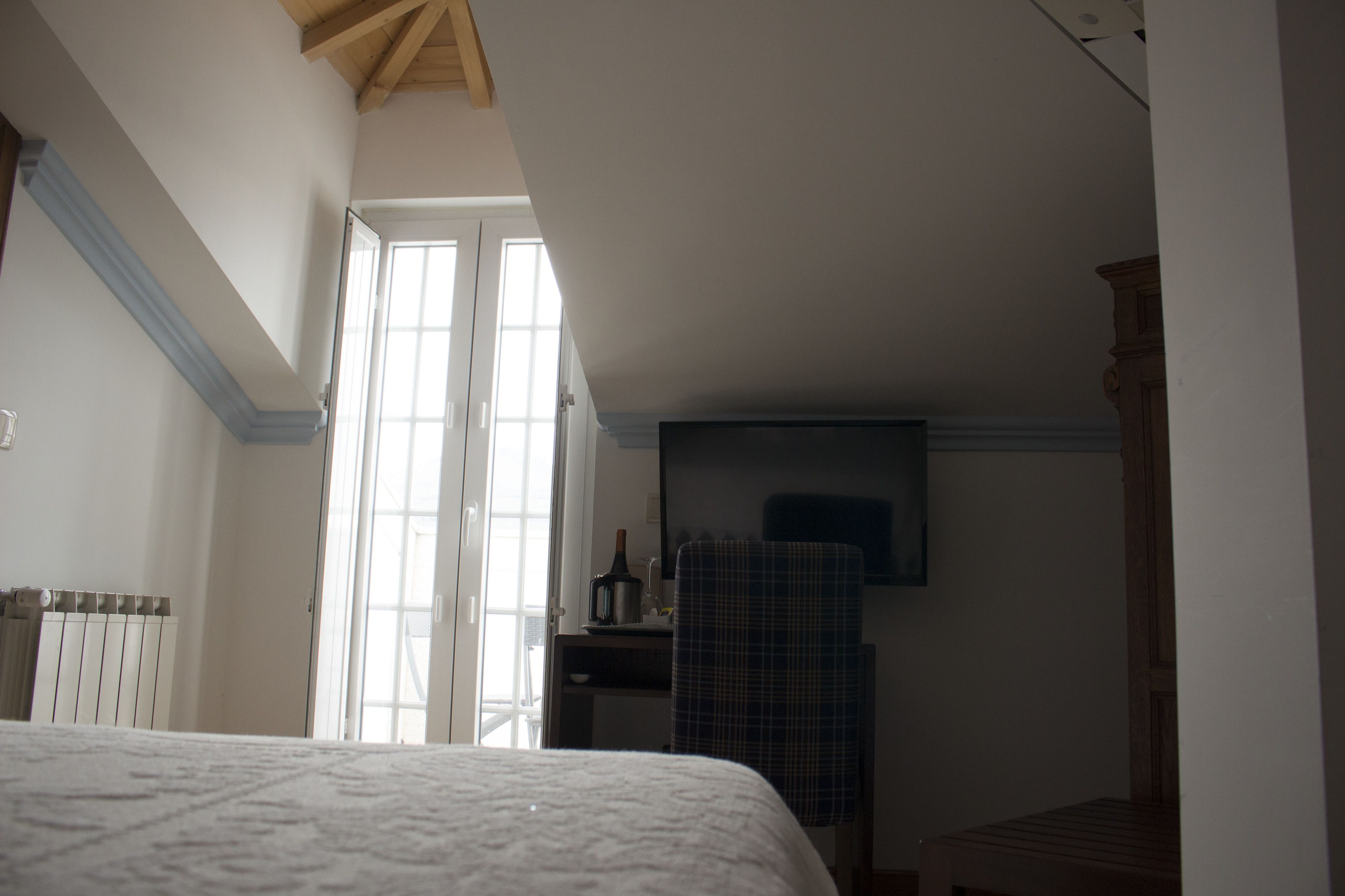 Quarto com cama, penteadeira, cadeira e janela.