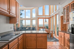 A modern kitchen with wooden cabinets, a large island, and a view of the outdoors.