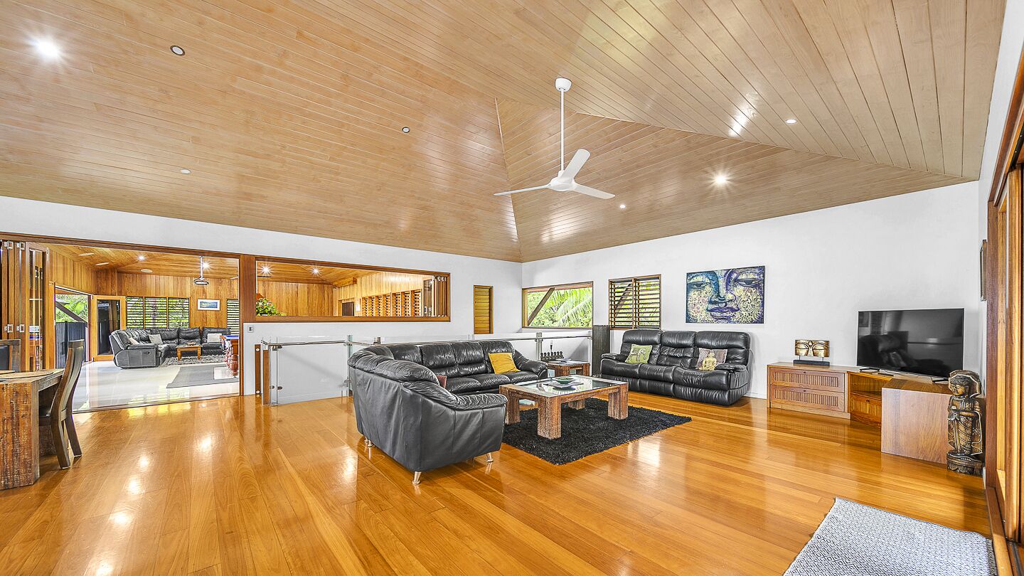 Ein geräumiger Wohnbereich mit Holzboden, Deckenventilator und einer großen schwarzen Ledersofa.