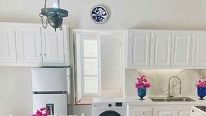 A kitchen with white cabinets, a washing machine, a sink, and a chandelier. - Alex's traditional summerhouse (Hydra)