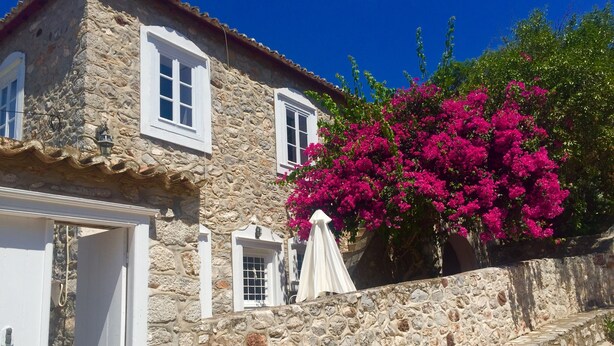 A stone building with white shutters and a door, a white umbrella, and vibrant pink bougainvillea flowers. - Alex's traditional summerhouse (Hydra)